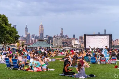 a crowd of people sitting on the grass in a park at PATHside 1BR Quick Access to NYC in Hoboken