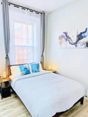 a bed in a bedroom with a large window at PATHside 1BR Quick Access to NYC in Hoboken