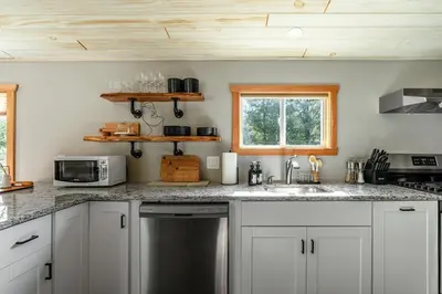 a kitchen with white cabinets and a sink and a microwave at Mural Art Cabin With Pond And Hot Tub in Narrowsburg