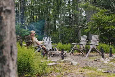 a young girl sitting in chairs in a park at Mural Art Cabin With Pond And Hot Tub in Narrowsburg