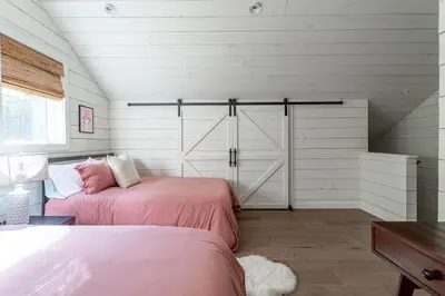 a bedroom with two beds and a barn door at Hare & Hollow with Hot Tub & Fenced Yard
