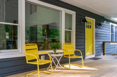 two yellow chairs and a table on a porch at Hare & Hollow with Hot Tub & Fenced Yard
