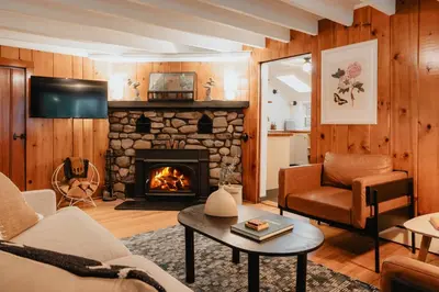 a living room with a stone fireplace at Creekfront Cabin Sauna & Hot Tub Hikers Hollow in Cuddebackville