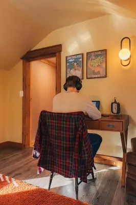 a man sitting at a desk with a computer at 1930's Vintage Cabin Hot Tub Kohler Cabin in Jeffersonville