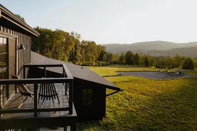 a house with a deck and a pond in a field at Onyx Ridge Breathtaking Views 14 Acres in Jeffersonville