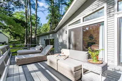 a patio with a couch and chairs on a deck at Riverfront Retreat Hot Tub, Firepit & Pool Table in Cuddebackville