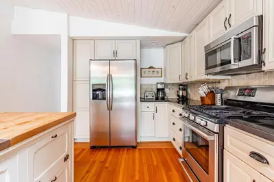 a kitchen with white cabinets and a stainless steel refrigerator at Riverfront Retreat Hot Tub, Firepit & Pool Table in Cuddebackville