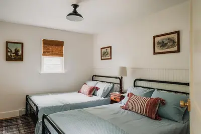 two beds in a room with white walls at Roebling House 1850s Cabin Hot Tub Fire Pit in Barryville