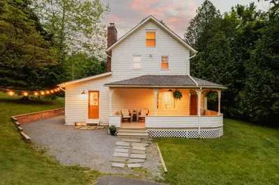 a white house with a patio in the yard at Roebling House 1850s Cabin Hot Tub Fire Pit in Barryville