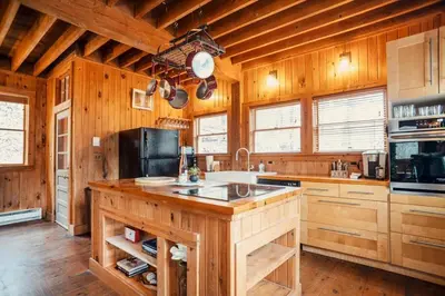 a large kitchen with wooden walls and wooden floors at Breathtaking River Views The Hawks Nest Cabin in Glen Spey