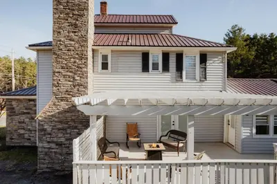 a white house with a porch with a white fence at Swan Pond Cabin Hot Tub & Firepit Retreat in Swan Lake