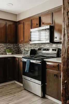 a kitchen with wooden cabinets and a stove top oven at Swan Pond Cabin Hot Tub & Firepit Retreat in Swan Lake
