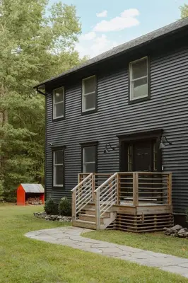 a black house with a porch and a deck at Woods Edge Private 5 Acres Hot Tub Fire Pit in Barryville