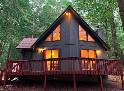 a tiny house in the woods with a large deck at Hot Tub & Fire Pit: Cozy Pines Chalet in Poconos in Locust Lakes Village