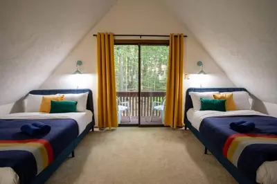two beds in a room with a balcony at Hot Tub & Fire Pit: Cozy Pines Chalet in Poconos in Locust Lakes Village