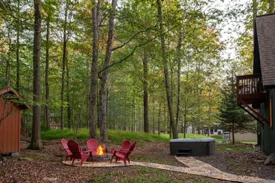 a fire pit in a yard with red chairs at Hot Tub & Fire Pit: Cozy Pines Chalet in Poconos in Locust Lakes Village