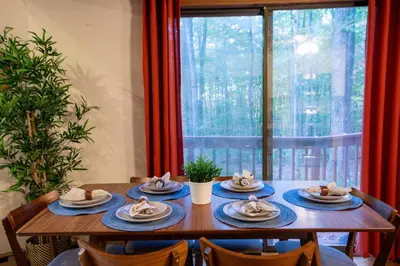 a table with plates of food on it in front of a window at Hot Tub & Fire Pit: Cozy Pines Chalet in Poconos in Locust Lakes Village