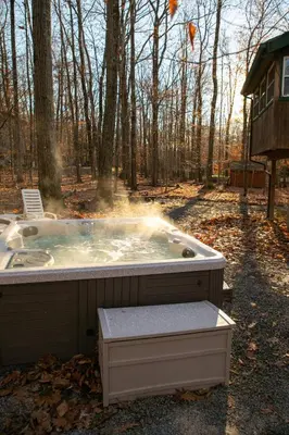 a jacuzzi tub in the woods next to a house at Hot Tub & Fire Pit: Cozy Pines Chalet in Poconos in Locust Lakes Village
