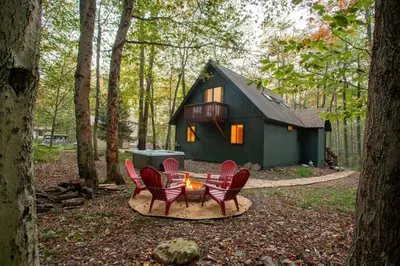 a group of chairs and a table in front of a cabin at Hot Tub & Fire Pit: Cozy Pines Chalet in Poconos in Locust Lakes Village