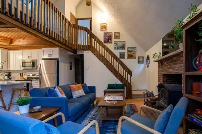 a living room with blue couches and a staircase at Hot Tub & Fire Pit: Cozy Pines Chalet in Poconos in Locust Lakes Village