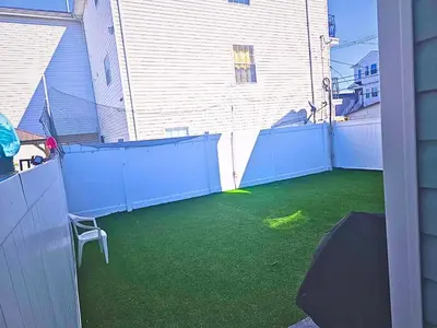 a backyard with a blue fence and green grass at Home away from home 5 minutes away EWR Airport in Elizabeth