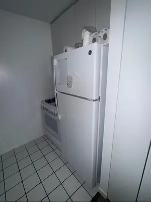 a small kitchen with a white refrigerator and a stove at LOFT IN WITH ALL AMENETIES BUILDING BEST LOCATION IN MIDTOWn in New York