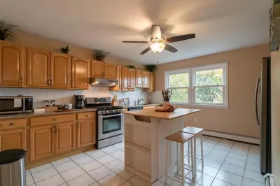 a kitchen with wooden cabinets and a ceiling fan at The Boulevard Stay! 25 mins to NYC! Spacious 2BR! in Harrison