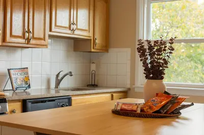 a kitchen counter with a vase of flowers on a table at The Boulevard Stay! 25 mins to NYC! Spacious 2BR! in Harrison