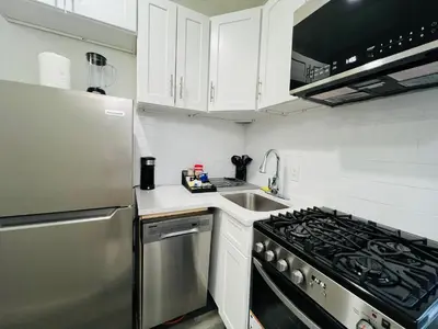 a kitchen with white cabinets and a stainless steel stove at VibeHaus Midtown in New York