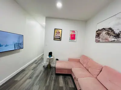 a living room with a pink couch and paintings at VibeHaus Midtown in New York