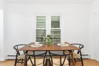 a dining room table with chairs and a window at Hamilton-15 mins to EWR, 20 mins PATH to NYC in Harrison