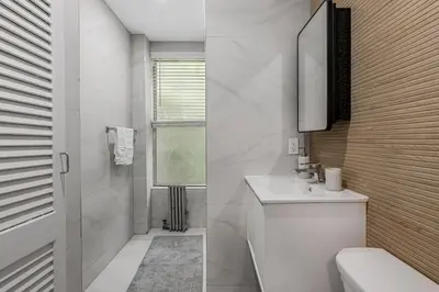a white bathroom with a sink and a mirror at Time Square Apartment in New York
