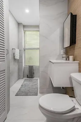 a white bathroom with a toilet and a sink at Time Square Apartment in New York
