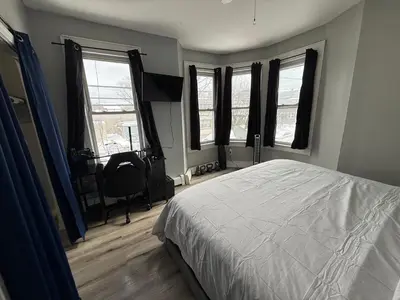 a bedroom with a bed and a desk and windows at EWRBNB - Private Bedroom in Well sized Shared Apartment - 1 in Elizabeth