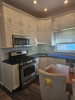a kitchen with white cabinets and a stove and a table at Cozy Getaway 2-Penn Station,NJPAC,Prudential Center in Kearny