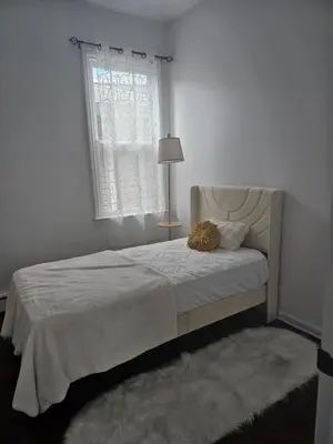 a white bedroom with a bed with a window at Cozy Getaway 2-Penn Station,NJPAC,Prudential Center in Kearny