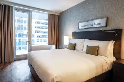 a large bed in a hotel room with a large window at The Bernic Hotel New York City,Tapestry Collection by Hilton in New York