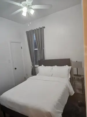 a bedroom with a white bed with a ceiling fan at Cozy Getaway 3-Prudential Center, NJPAC, Penn Station in Kearny