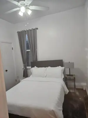 a bedroom with a white bed with a ceiling fan at Cozy Getaway 3-Prudential Center, NJPAC, Penn Station in Kearny