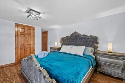 a bedroom with a large bed with a blue blanket at Cozy Farmhouse - Fireplace, Backyard, BBQ, Games - 3 MIN TO CAMELBACK in Tannersville