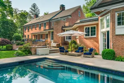 a swimming pool with chairs and an umbrella in front of a house at Luxury Princeton Estate Pool, Hot Tub, Sleeps 20 in Princeton
