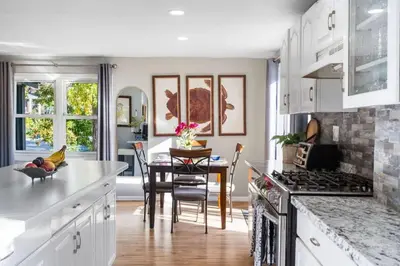a kitchen with white cabinets and a dining room with a table at 4BR Home Minutes to NYC Time Square in Teaneck