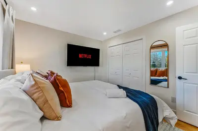 a bedroom with a white bed with a tv on the wall at Emerald Luxe Retreat Lake Hot Tub Sauna in Long Pond