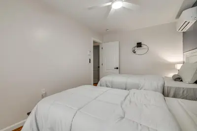 a white bedroom with two beds and a ceiling fan at Waterfront Arrowhead Lake Retreat with Resort Perks! in Pocono Lake