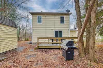 a house with a picnic table and a grill in front of it at Waterfront Arrowhead Lake Retreat with Resort Perks! in Pocono Lake