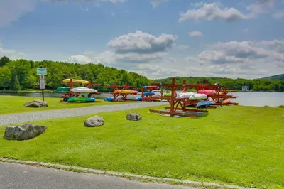a group of picnic tables in a park next to a lake at Waterfront Arrowhead Lake Retreat with Resort Perks! in Pocono Lake