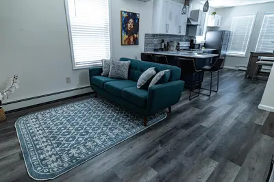 a living room with a green couch and a kitchen at Cozy Urban Oasis Near NYC in West New York