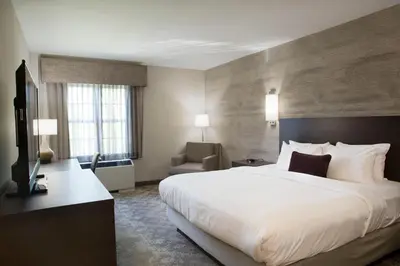 a hotel room with a large bed and a chair at Normandy Farm Hotel & Conference Center in Blue Bell