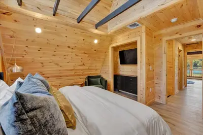 a log cabin bedroom with a bed and a tv at Lakefront AFrame, Heated Pool, Spa, Sauna, Theatre in Blakeslee