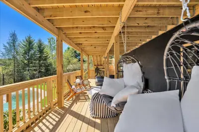 a porch with a swinging couch on a wooden deck at Lakefront AFrame, Heated Pool, Spa, Sauna, Theatre in Blakeslee